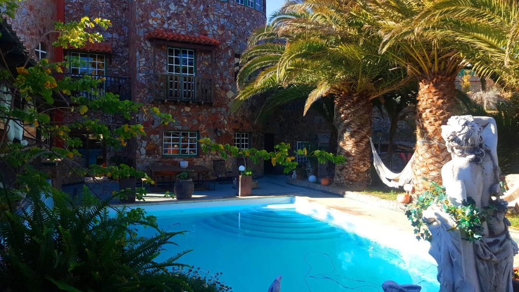 a swimming pool in front of a building with palm trees at Finca Tropical in Arico Viejo