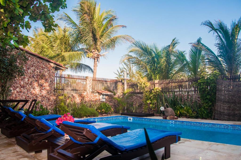una piscina con sillas azules y palmeras en Pousada Vento de Jeri, en Jericoacoara