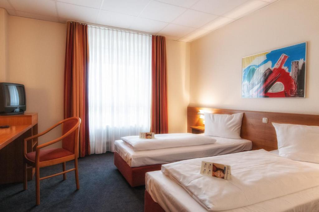 Cette chambre comprend deux lits et une télévision. dans l'établissement Center Hotel Drive Inn, à Hirschaid
