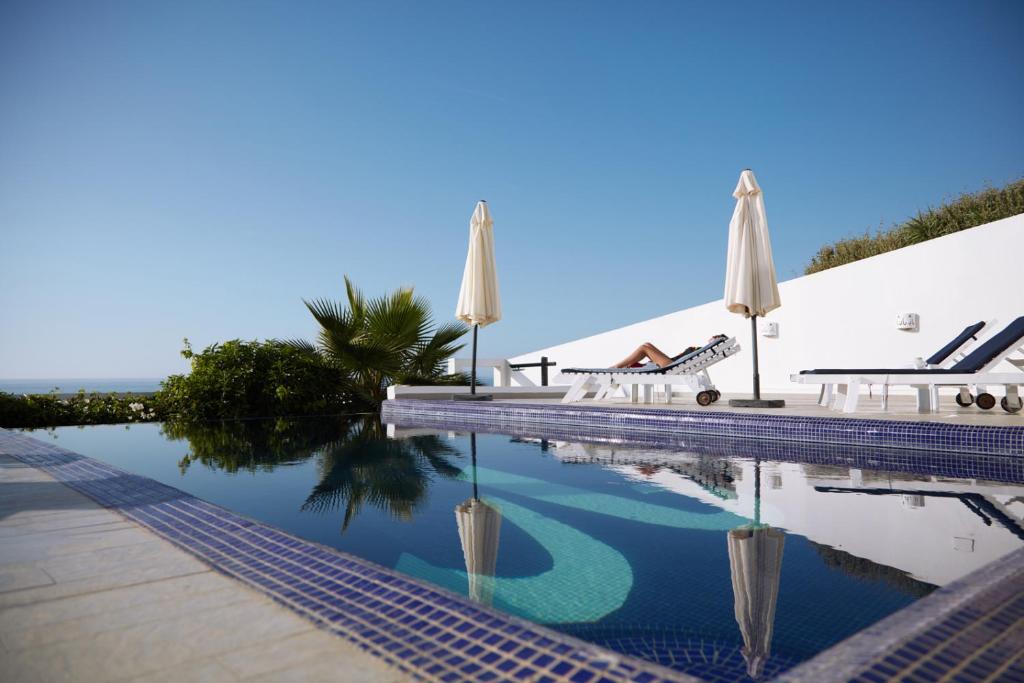a swimming pool with umbrellas and a table and chairs at Vila Bea in Moulay Bousselham