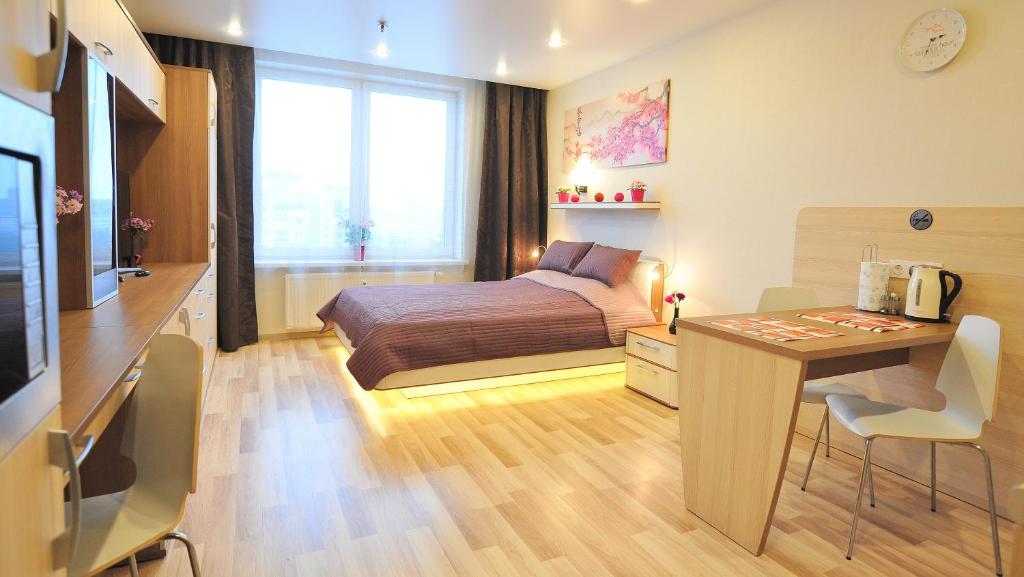 a bedroom with a bed and a desk and a table at Apartment Evia Nord in Saint Petersburg