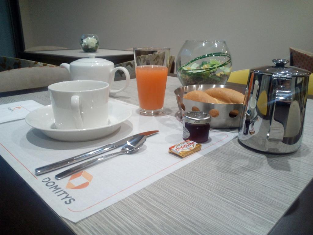 a table with a breakfast tray with a coffee maker and juice at Résidence Séniors Domitys Les Hautes Feuilles in Reims