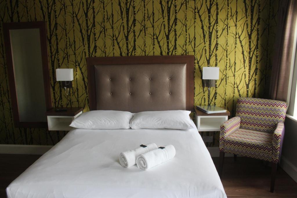 two rolls of toilet paper on a bed with a chair at St. Judes Lodge B&B in Galway