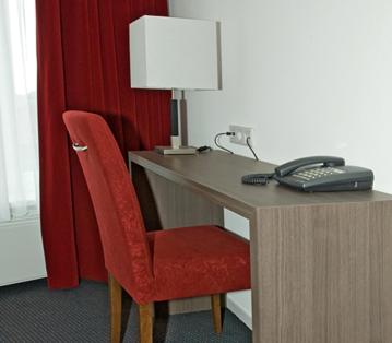 a desk with a chair and a lamp on it at Hotel Bonaventure in Vlissingen