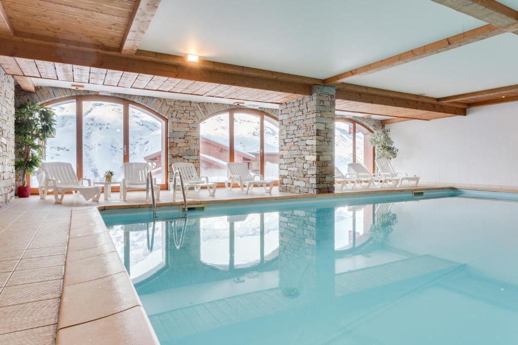 a swimming pool in a house with a brick wall at Residence Chalet de l'Adonis in Les Menuires
