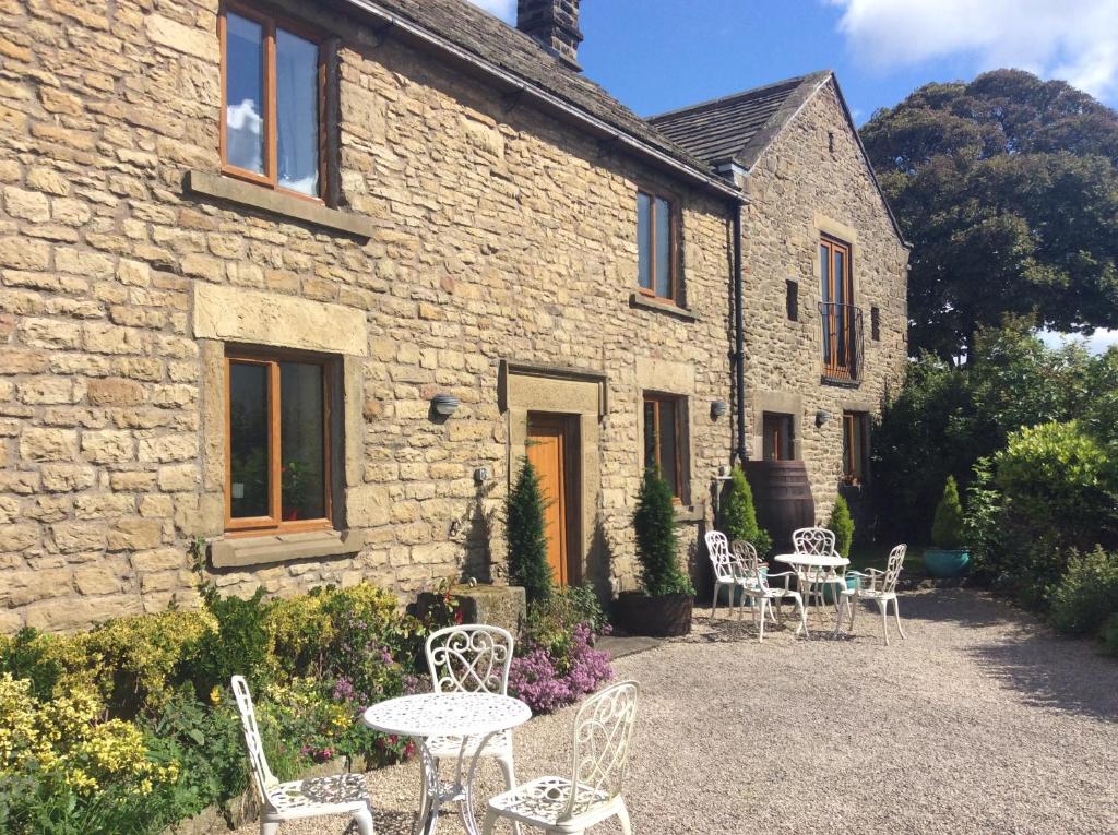 a stone building with chairs and tables in front of it at Bretton Cottage in Eyam