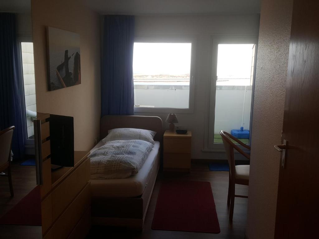 Hotel Panorama Garni في هيلغولاند: غرفة نوم صغيرة بها سرير ونوافذ