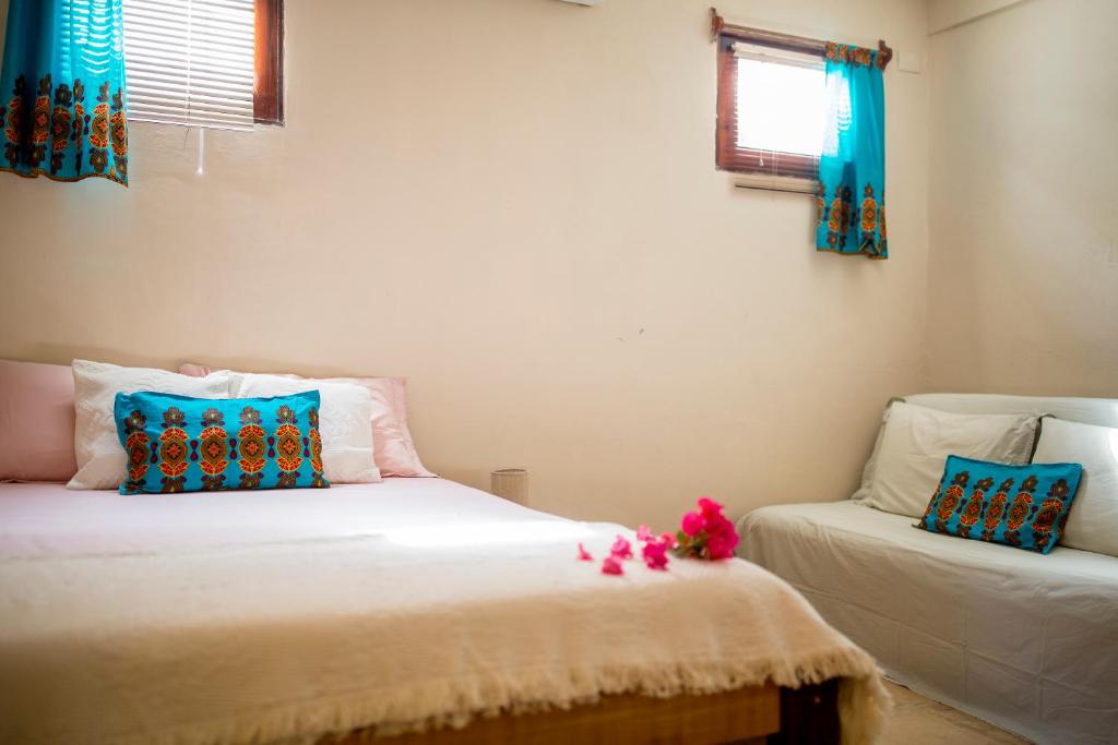 um quarto com 2 camas e uma janela com cortinas azuis em Casa Bougainvilla em Jericoacoara