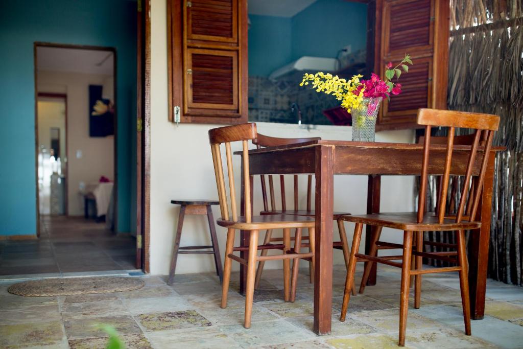 une table avec des chaises et un vase de fleurs. dans l'établissement Casa Bougainvilla, à Jericoacoara