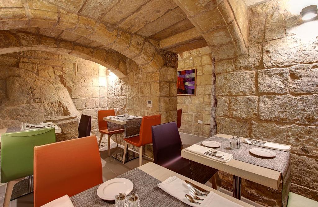 een restaurant met tafels en stoelen en een stenen muur bij Palazzo Paolina Boutique Hotel in Valletta