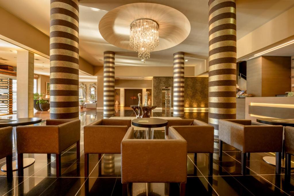 a lobby with columns and tables and a chandelier at Congo Palace in Athens