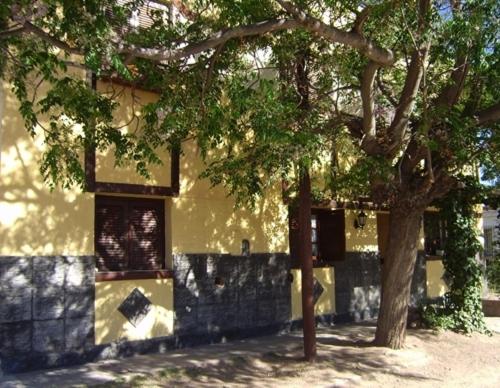een geel gebouw met een boom ervoor bij Hostería Las Gemelas in Capilla del Monte