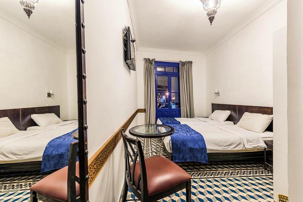 a hotel room with two beds and a chair at Hôtel Central in Casablanca