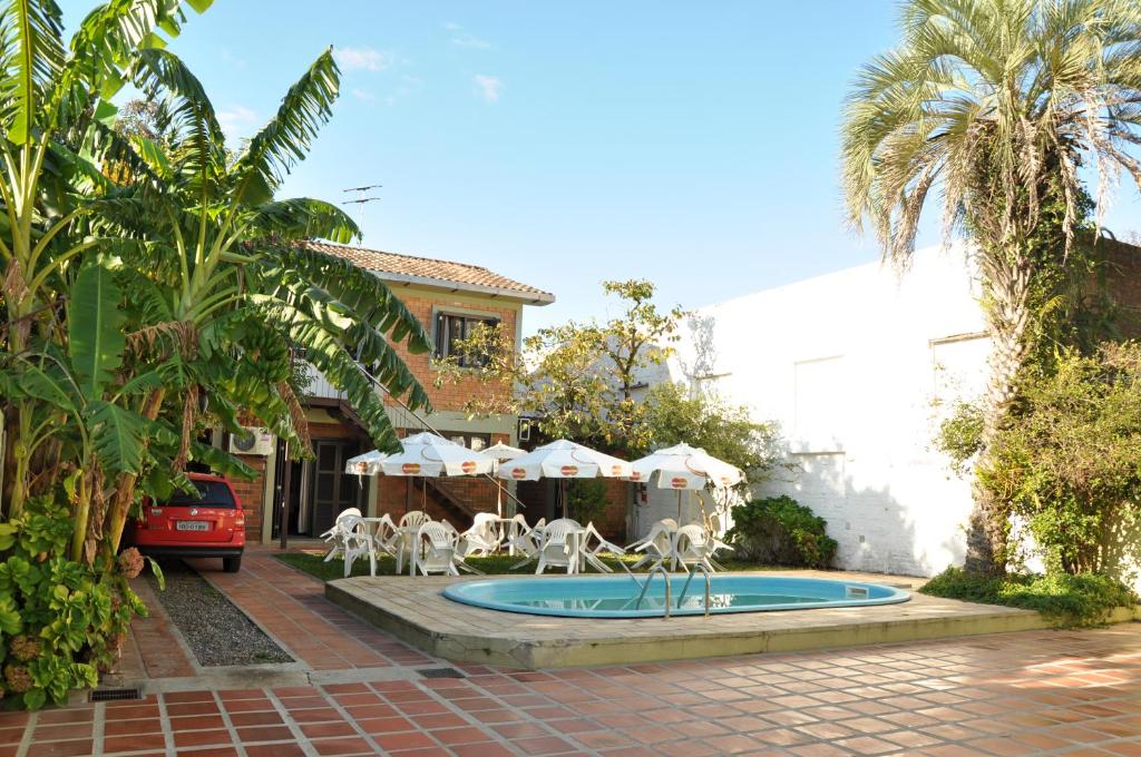 una piscina con sillas y sombrillas frente a una casa en Hotel Nelly, en São Gabriel