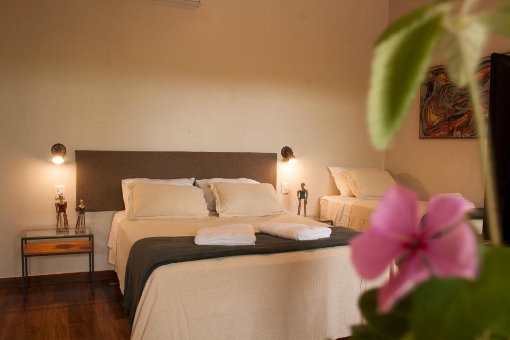 a bedroom with two beds with white sheets and a pink flower at Villa Domaso in Brumadinho