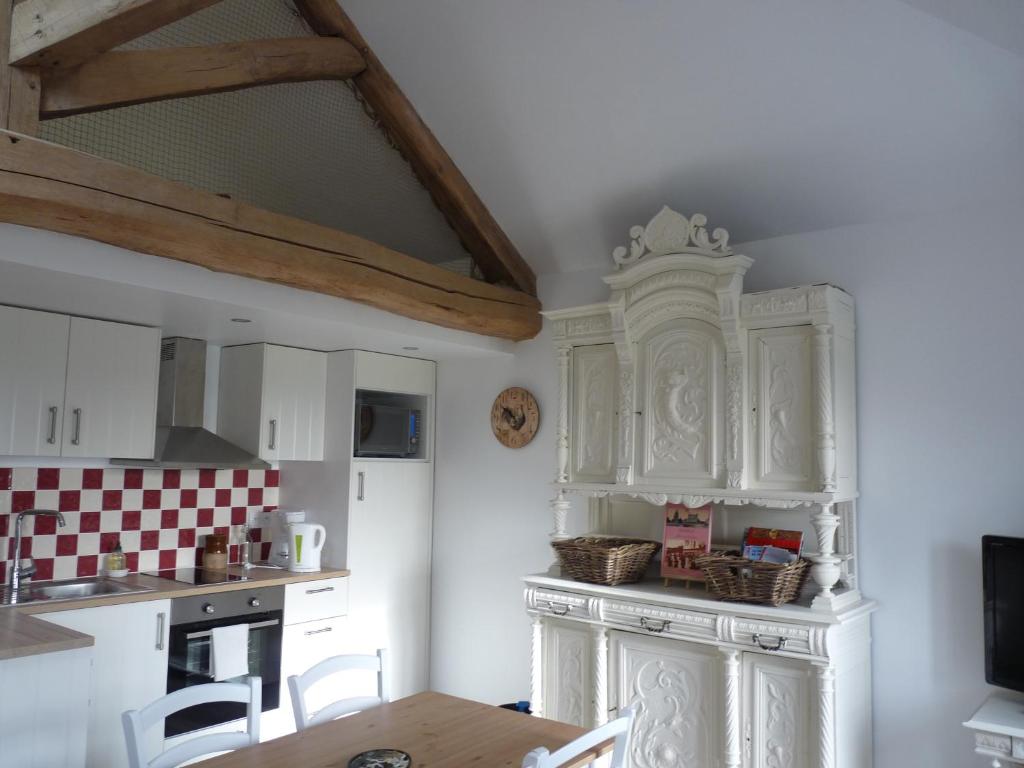 a kitchen with white cabinets and a table with chairs at L'Etable d'Orgerus in Orgerus