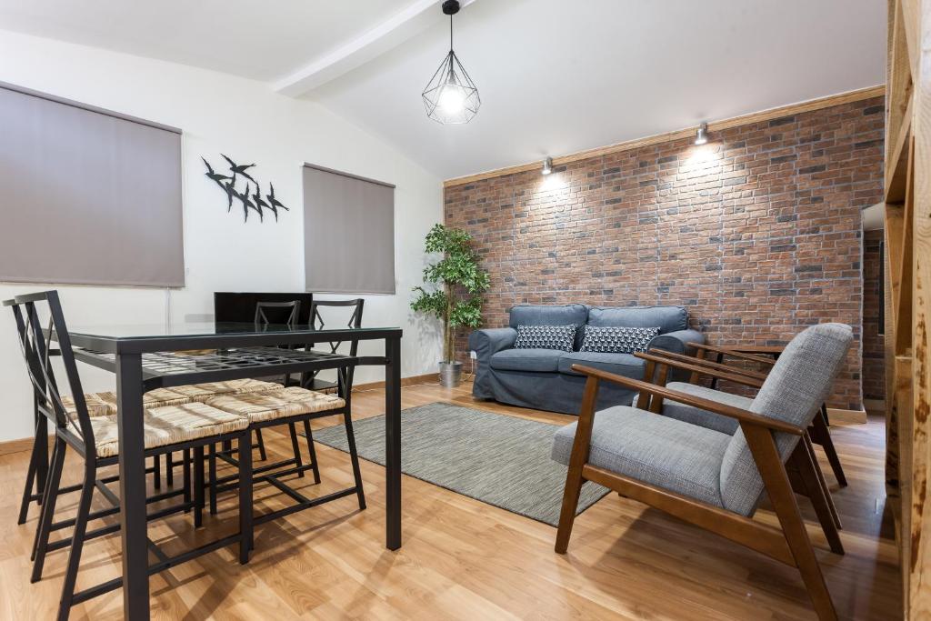 een woonkamer met een tafel en stoelen en een bakstenen muur bij FLH Bairro Alto Stylish Apartment in Lissabon