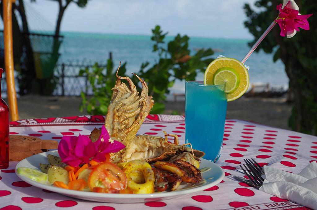 a plate of food on a table with a drink at Kimte Beach Lodge in Jambiani