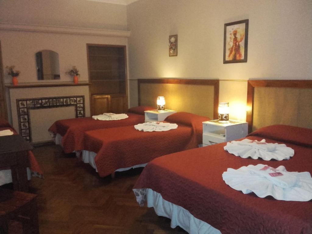 Habitación de hotel con 3 camas con sábanas rojas en Posada La Casona en Salta