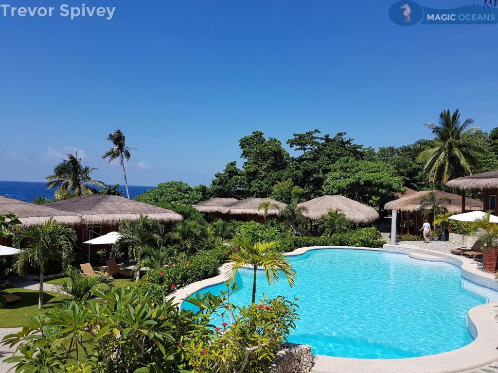 a swimming pool at a resort with umbrellas at Magic Oceans Dive Resort in Anda