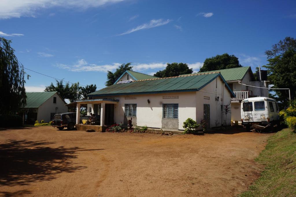 a white house with a green roof on a dirt road at Masaka Backpackers, Tourists Cottage & Campsite in Masaka