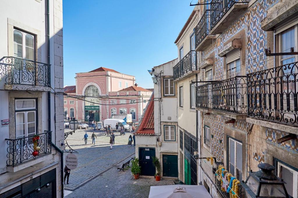 eine Stadtstraße mit Gebäuden und Menschen, die auf der Straße spazieren in der Unterkunft Charming Apartment in Alfama in Lissabon