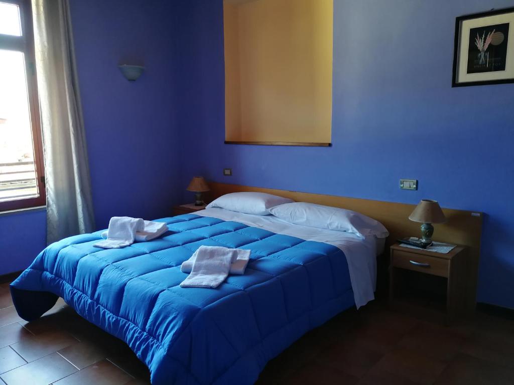 a blue bedroom with a bed with towels on it at Al 182 in Fornaci di Barga