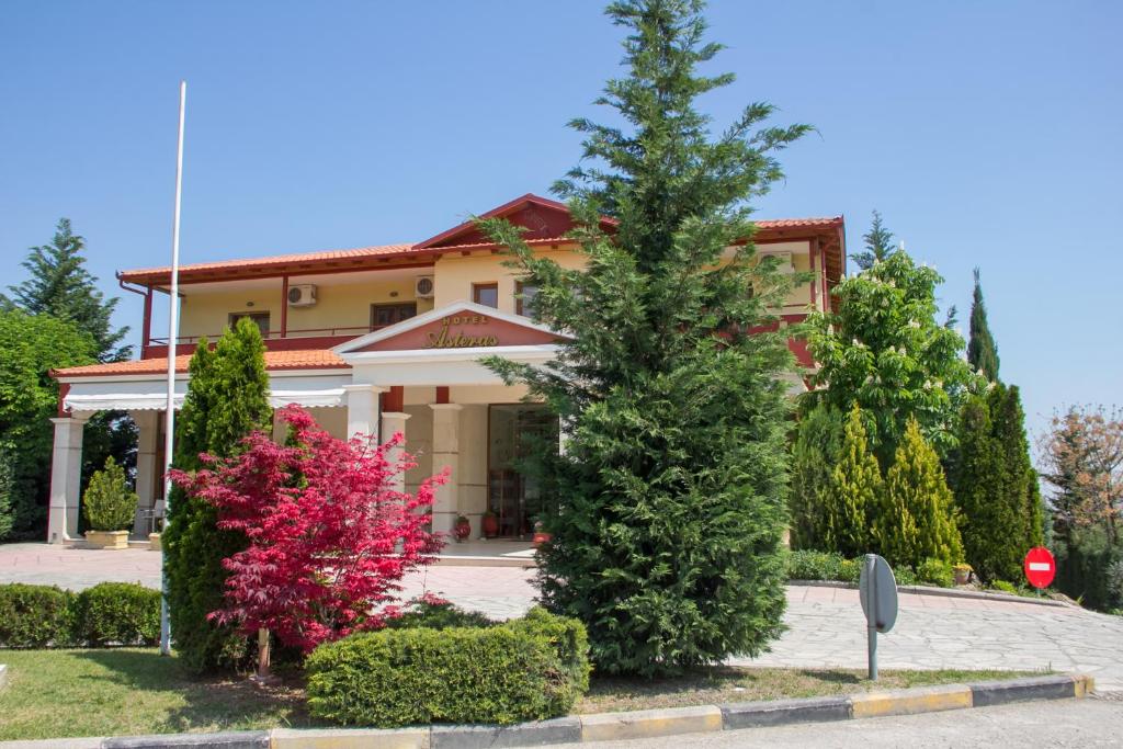 una casa con árboles y arbustos delante de ella en Asteras Hotel, en Nausa