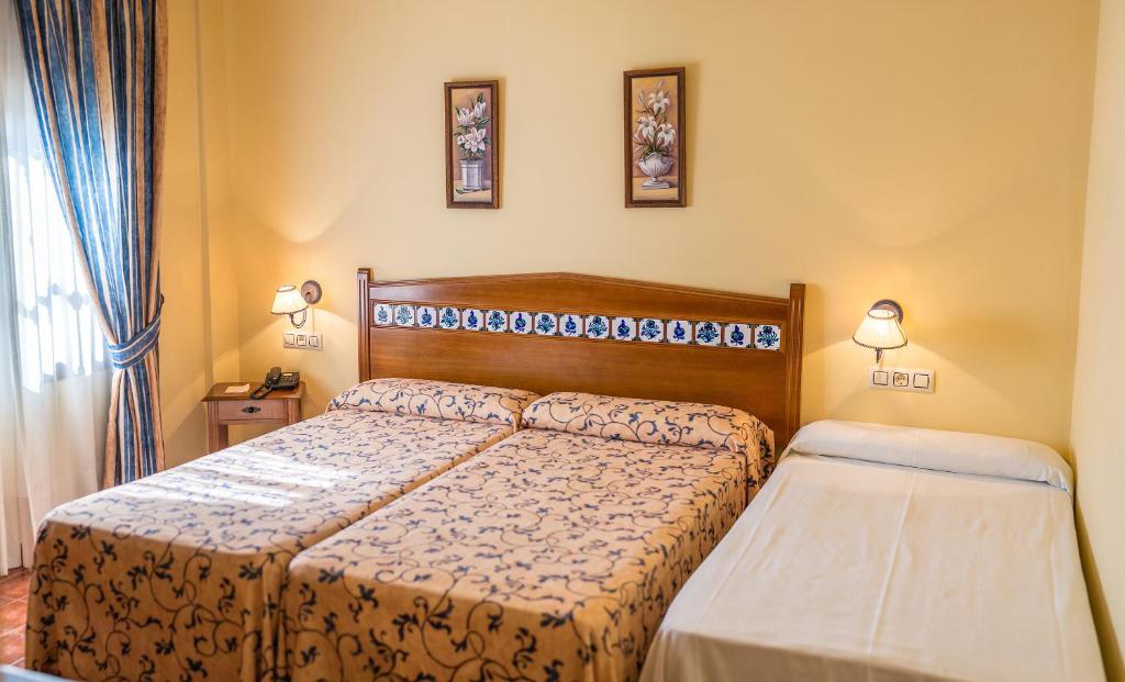 sypialnia z 2 łóżkami i 2 lampkami na ścianie w obiekcie Cortijo De Tajar w mieście Huétor-Tájar