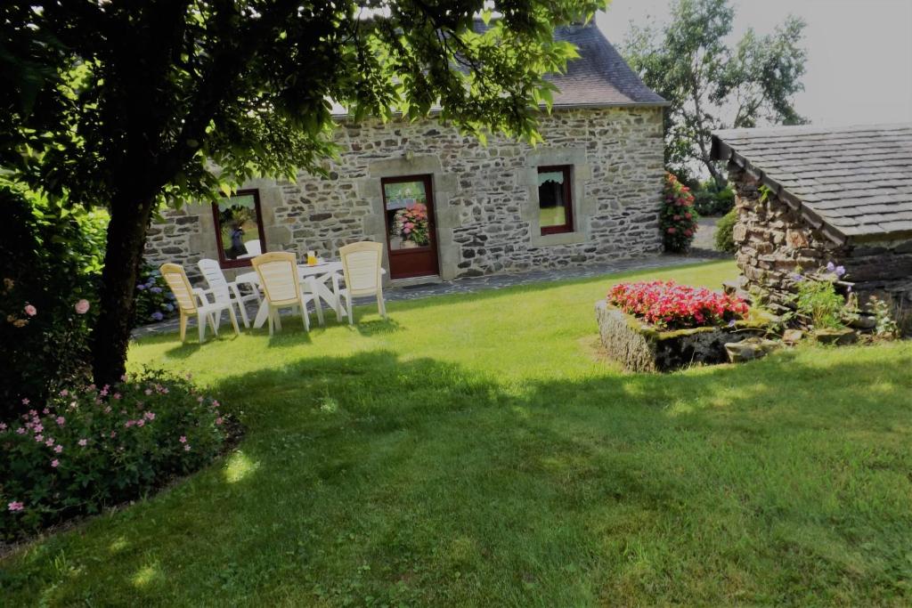 a table and chairs in the yard of a stone house at Gite De Penn Ar Stank in Pont-de-Buis