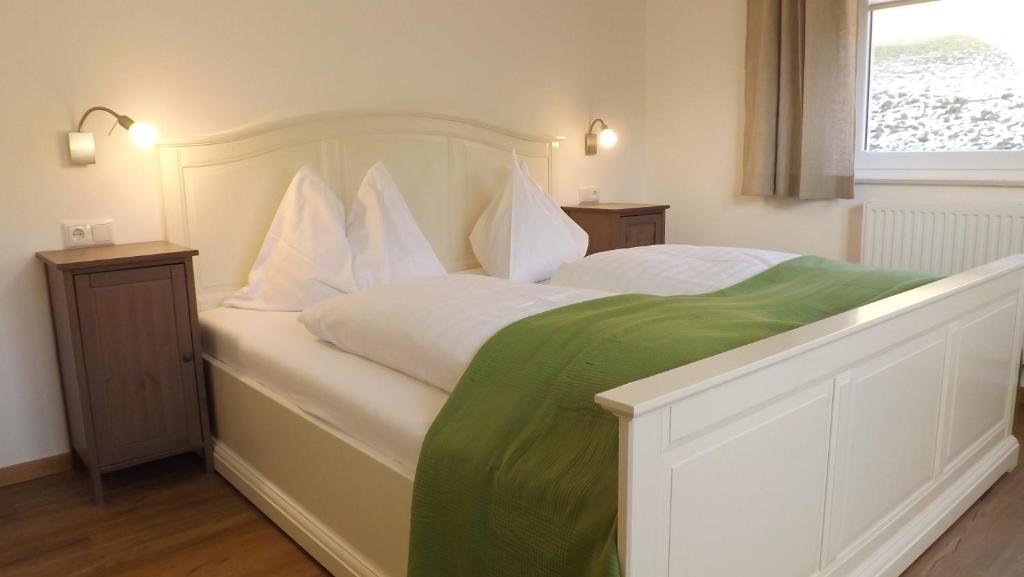 a bedroom with a white bed with a green blanket on it at Pension Geissler-Reicher in Oberwölz Stadt