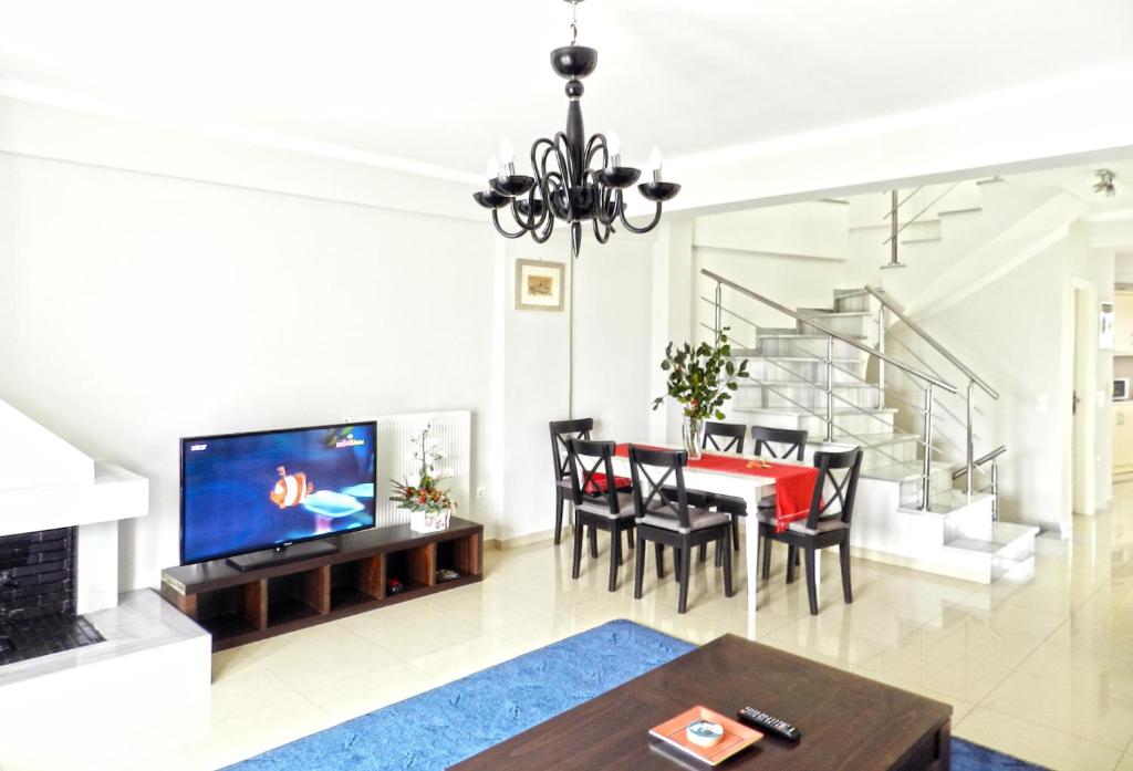 Una sala de estar con una mesa de comedor y un televisor. en Villa Nafplio, en Nauplia