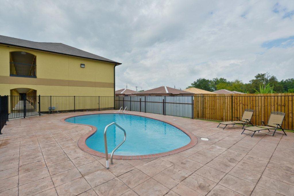 - une piscine avec 2 chaises et une clôture dans l'établissement Americas Best Value Inn Lake Charles Interstate 210, à Lake Charles