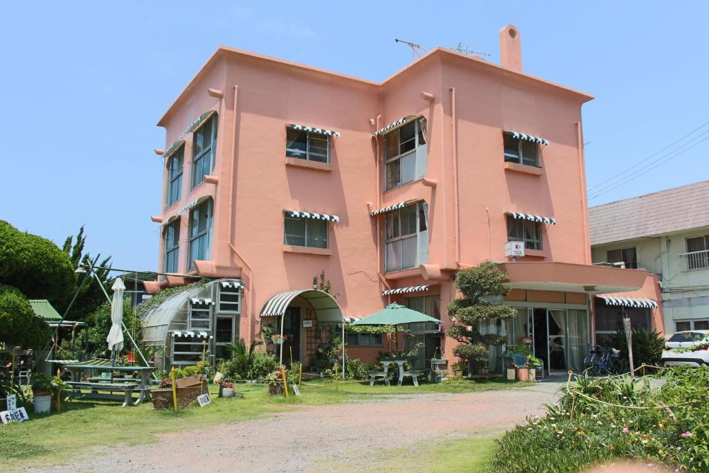 een roze gebouw met tafels ervoor bij Minamiboso Sirahama Club in Minamiboso