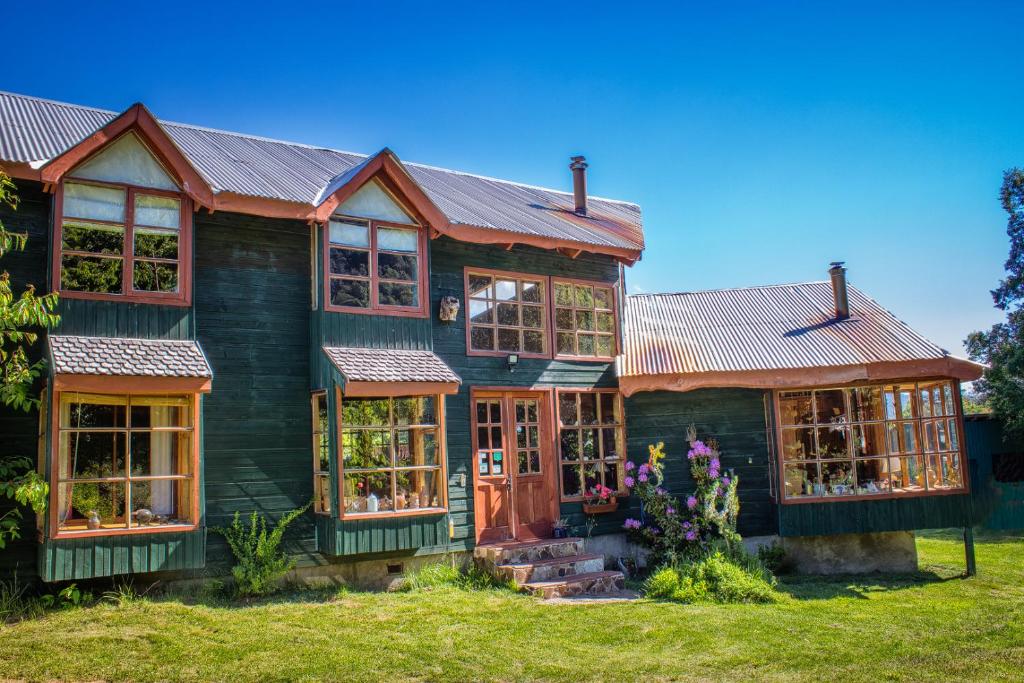 una casa con techo de metal y ventanas en CasaVerde Hostal Ecologico, en Malalcahuello