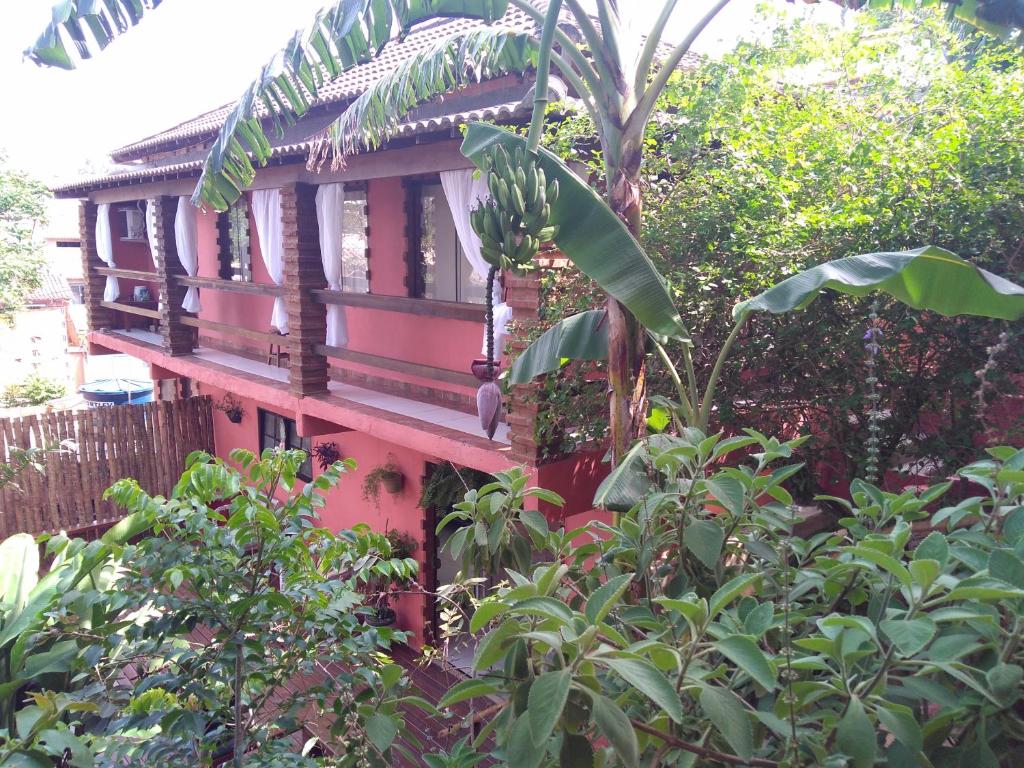 ein rotes Haus inmitten eines Gartens in der Unterkunft L&M Housing Apartamentos y casa in Búzios