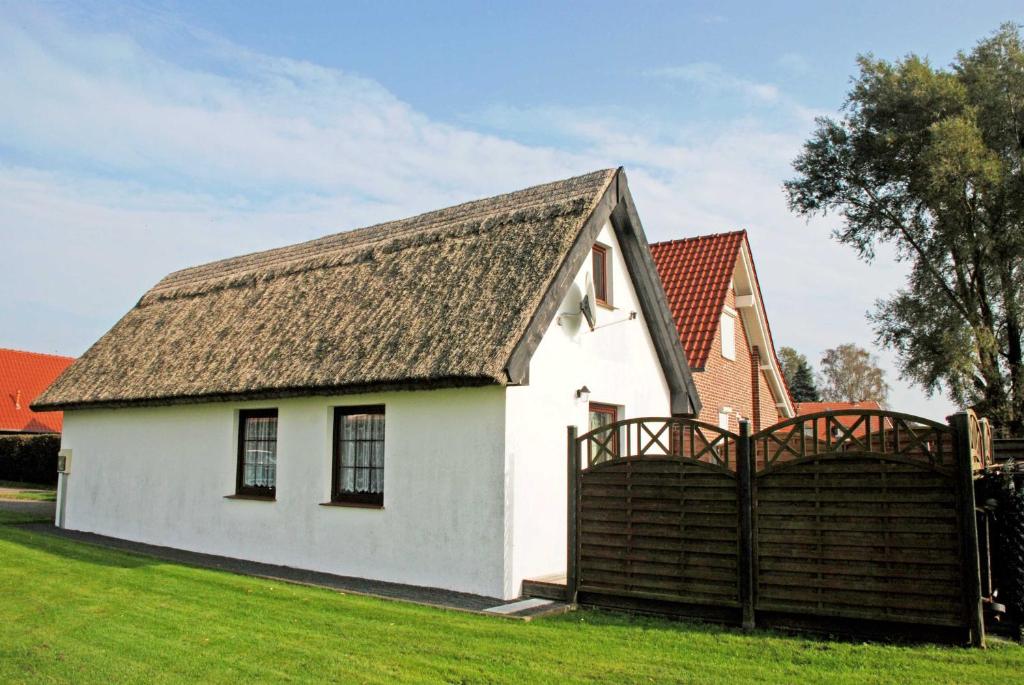 ロープベにあるFerienhaus mit Reetdach am Lobberの茶色の屋根の小さな白い家