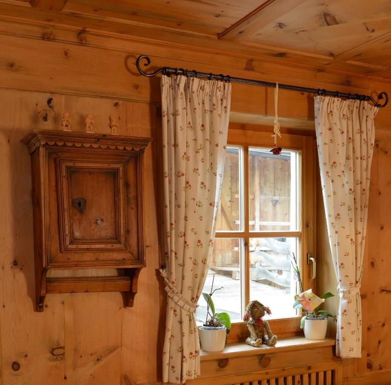 a window with curtains and plants on a window sill at Agriturismo Maso Larciunei in Selva di Val Gardena
