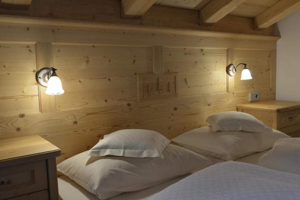a bedroom with a bed with two pillows and two lights at Agriturismo Maso Larciunei in Selva di Val Gardena