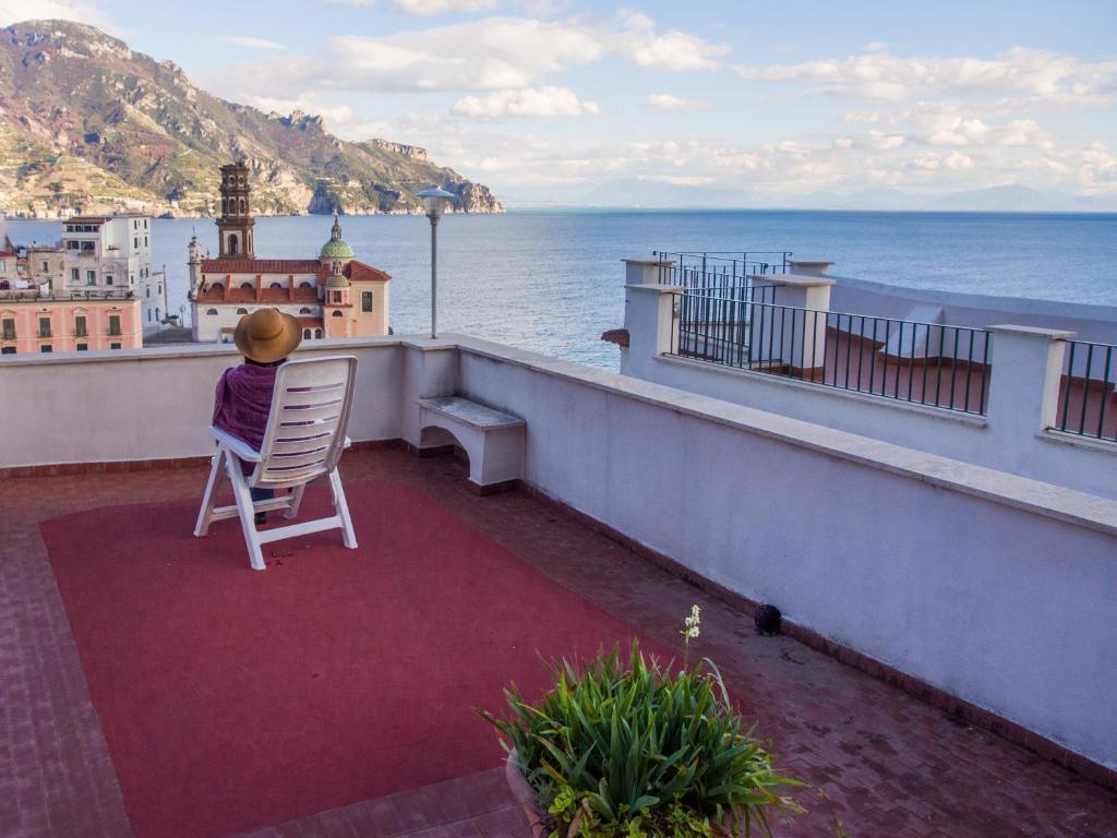 uma pessoa sentada numa cadeira numa varanda com vista para o oceano em Casa Almagio - Atrani Amalfi coast - terrace & seaview em Atrani