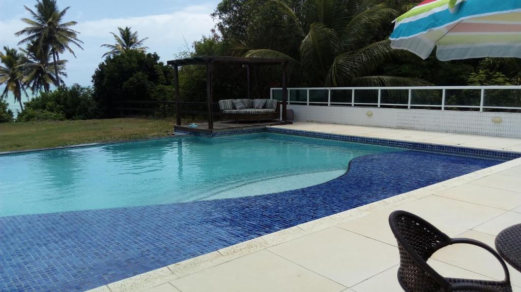 a swimming pool with a chair and an umbrella at Brisa de Carapibus in Conde