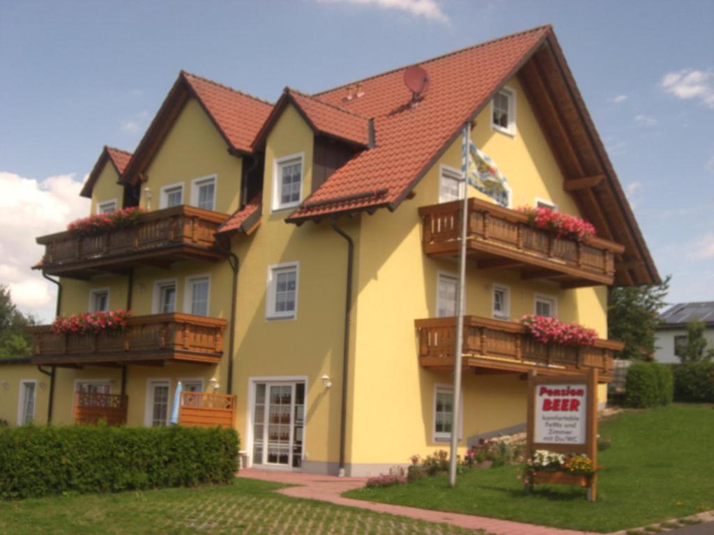 Una casa amarilla con balcones de madera. en Pension Beer, en Mähring