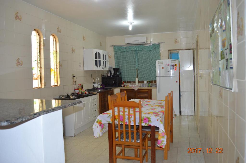 cocina con mesa, sillas y nevera en Pousada M&J, en São Gabriel