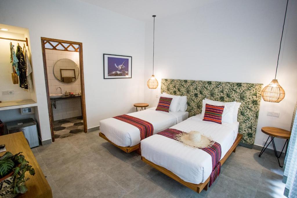 een hotelkamer met 2 bedden en een badkamer bij Abdi Hotel in Gili Trawangan