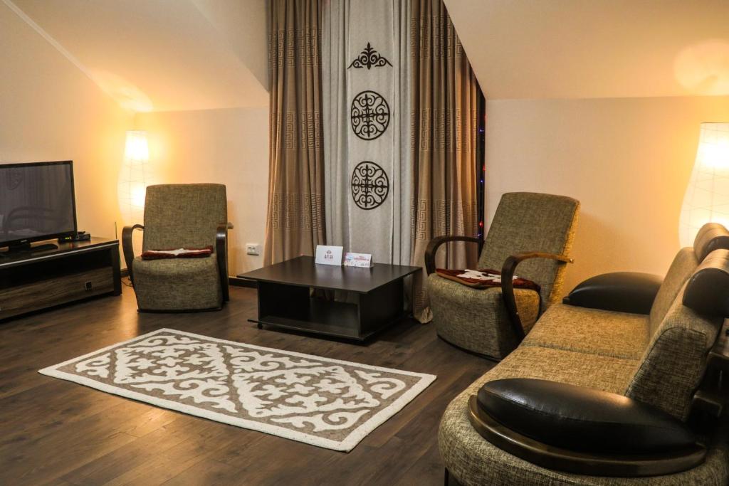 a living room with a couch and chairs and a tv at Guest house Altay in Karakol