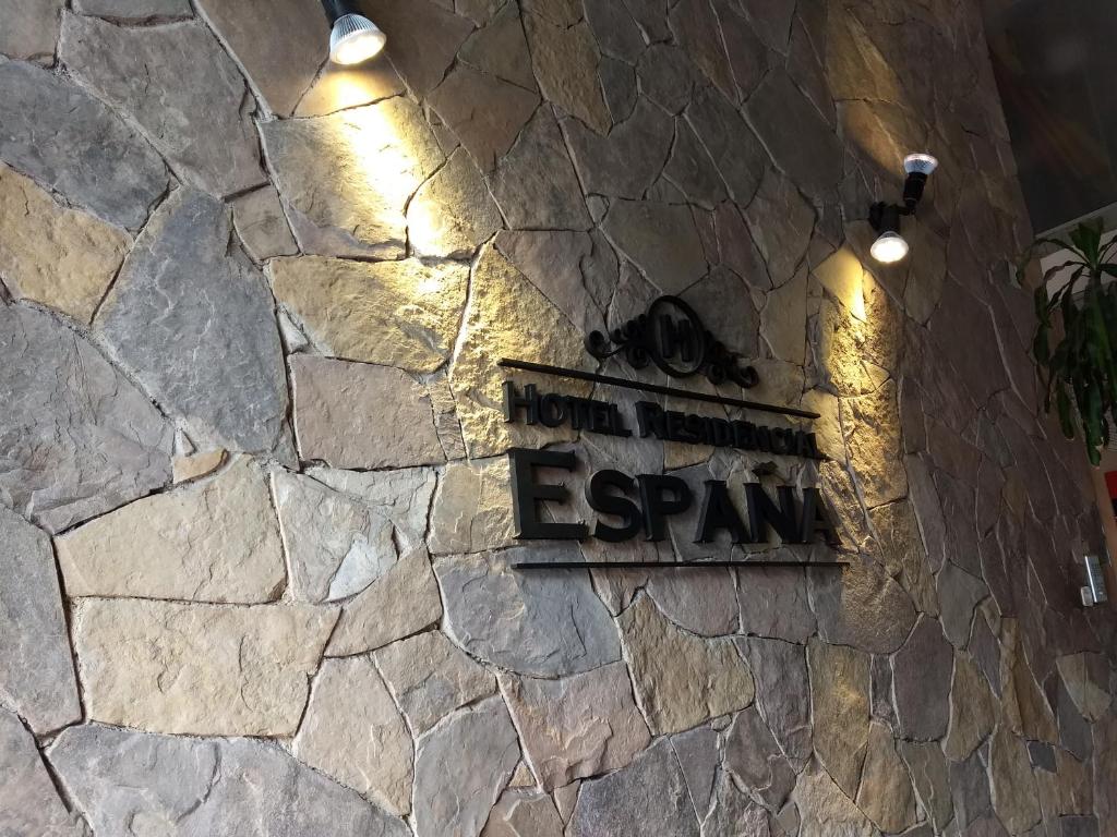 una señal en el lateral de una pared de piedra con luces en Hotel Residencial España en Salta