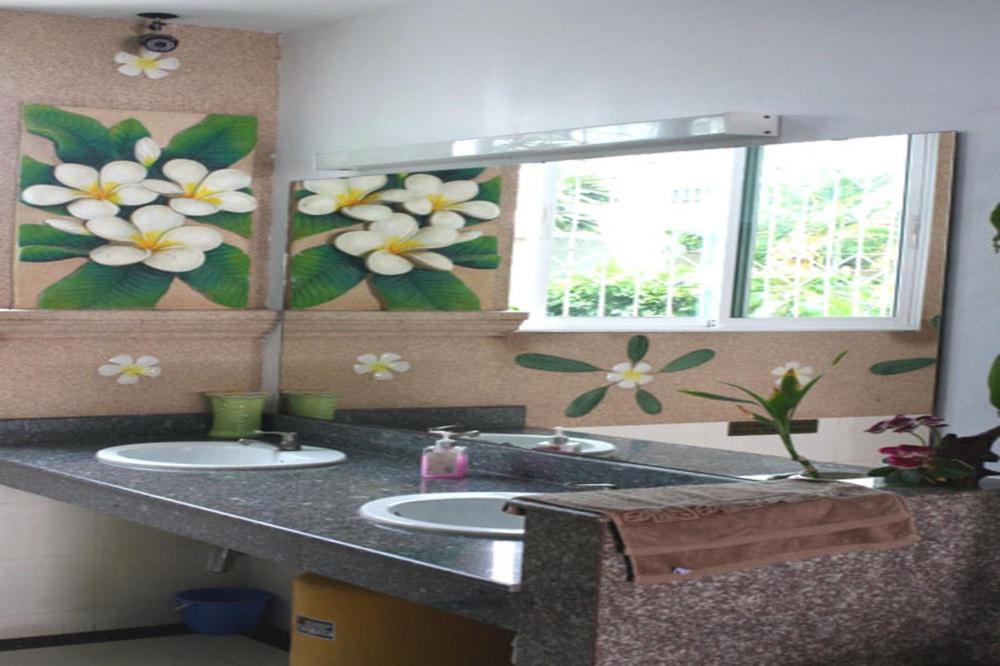 a bathroom with two sinks and flowers on the wall at Cha Am Perfect in Cha Am