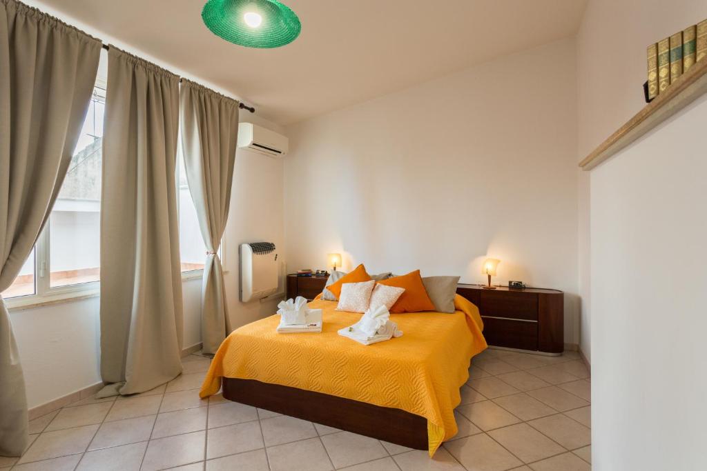 una camera da letto con un letto con lenzuola arancioni e una finestra di Case Spazioscena - Polimnia a Castelbuono