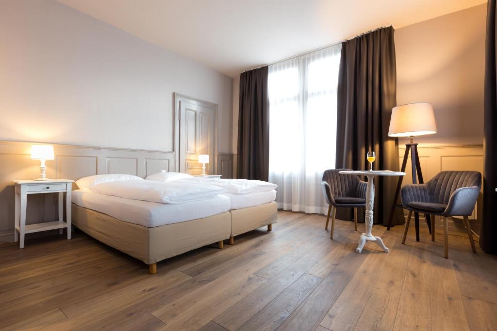 1 Schlafzimmer mit einem Bett, 2 Stühlen und einem Fenster in der Unterkunft Hotel Emmental in Thun