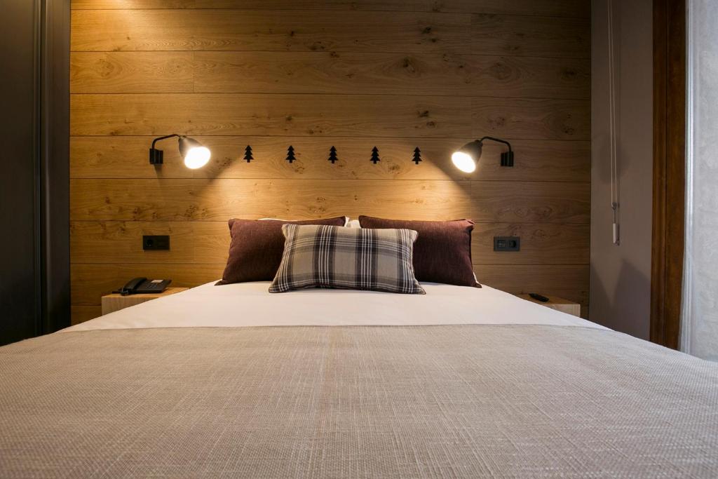 a bedroom with a bed with two lights above it at Hotel Xalet Montana in Soldeu